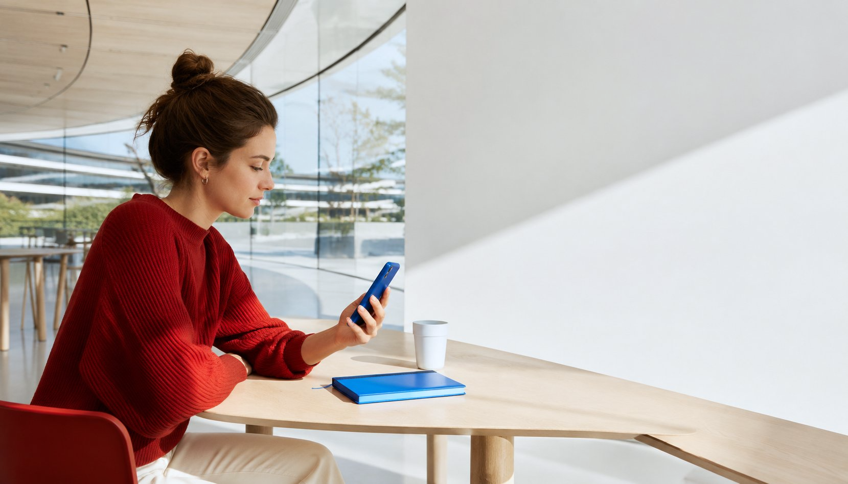 A woman checking her phone in a bright modern campus interior